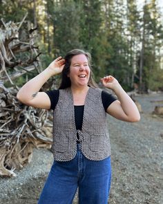 a woman standing in front of a pile of driftwood with her hands on her head