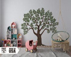 a child's room with a tree decal on the wall and a pink toy car