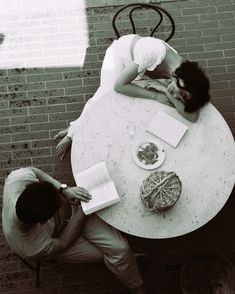 two people sitting at a table with an open book