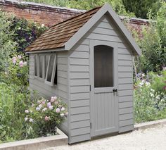 a small gray shed sitting in the middle of a garden