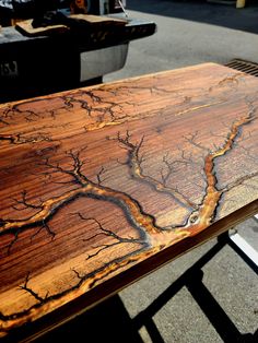 a wooden table that has some kind of design on it and is sitting in the middle of a street