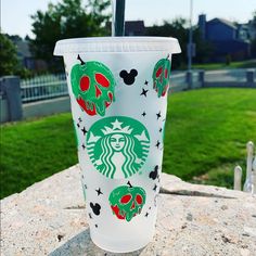 a starbucks cup with skulls on it sitting on top of a stone table in front of a grassy area