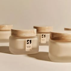 three jars with labels on them sitting next to each other in front of a white wall