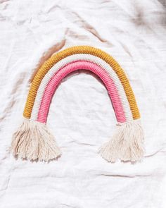 a pink, yellow and white rainbow shaped object with tassels