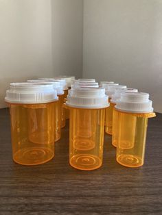 six yellow plastic bottles with white lids on a table