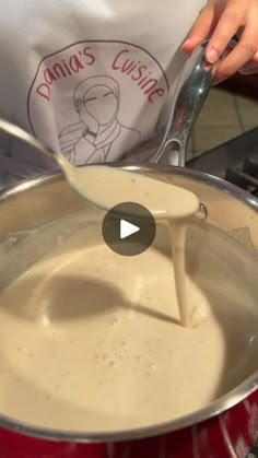 a person pouring milk into a pot on the stove with a ladle in it