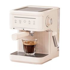 a white coffee maker with a cup filled with liquid