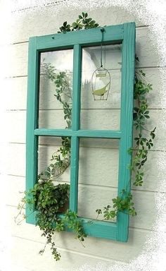 an old window is decorated with greenery and hanging on the wall