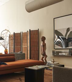 a living room with orange couches and art on the wall behind it in front of a wooden sculpture