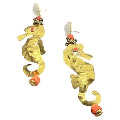 two gold seahorses with coral beads on their ear ends, one in the shape of a fish