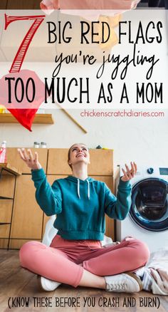 a woman sitting on the floor in front of a washing machine with her hands up