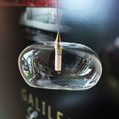 a close up of a glass object hanging from a ceiling fixture with a light bulb attached to it