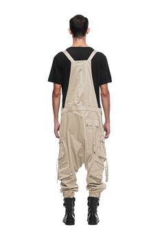 Overalls by JONNY COTA have arrived this season, crafted from luxe stretch cotton with customized Jonny Cota engraved hardware. Front pocket at chest Dual asymmetrical button slash pockets at hip Single cargo pocket on each leg Single pocket on back 95% cotton/5% spandex SIZE + FIT Loose, tapered, drop crotch fit Elastic cuffs The model is 6'2 and wearing a size M CARE Hand wash cold with colors, lay flat to dry