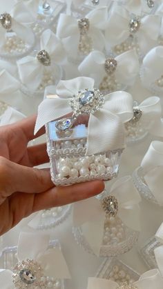 a person is holding a small box with pearls and bows on it, surrounded by other ornaments