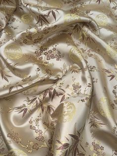 a close up view of the fabric with flowers and leaves in gold on white background