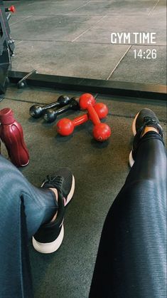 two people sitting on the ground with their feet propped up next to each other and some gym equipment