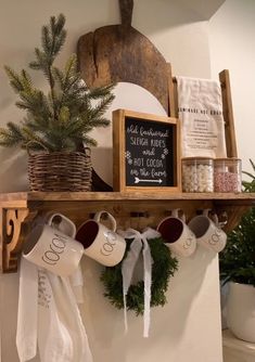 coffee mugs are hanging on the mantle in front of a potted christmas tree