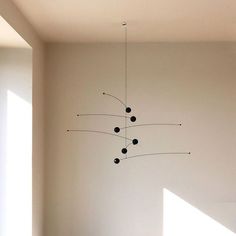 a modern chandelier hanging from the ceiling in an empty room with white walls