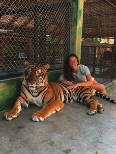 a woman sitting on the ground with a large tiger