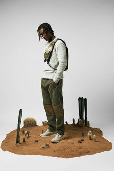 a man standing on top of a pile of dirt next to cactus plants and cacti