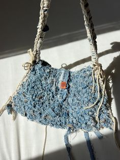 a handbag made out of old jeans and rope is hanging on a white wall