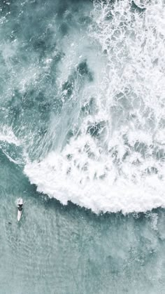 two surfers are riding the waves on their surfboards in the ocean, top view from above