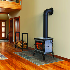 a wood burning stove sitting in the middle of a living room next to a stair case