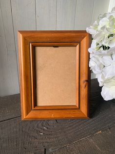 a wooden frame sitting next to a bouquet of white flowers