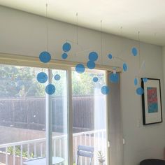 a living room filled with furniture and blue balls hanging from the ceiling next to a sliding glass door