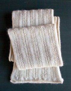 two white knitted scarves sitting on top of each other