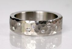 a close up of a wedding ring on a white surface with diamonds in the middle