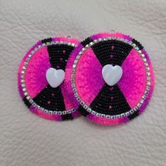 pair of pink and black beaded earrings with white heart on each earring hole