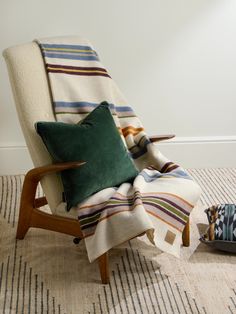 a chair with a striped blanket on top of it next to pillows and a pillow