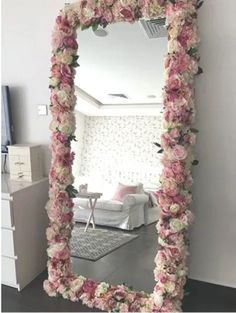 a mirror that has flowers on it in front of a white couch and rugs