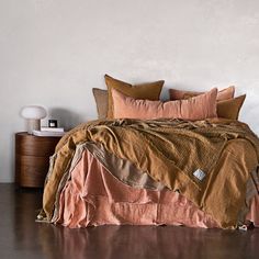 a bedroom with a bed covered in brown and pink linens, pillows and blankets