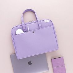 an apple laptop computer sitting on top of a desk next to a purple bag and wallet