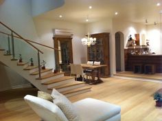 a living room filled with furniture and a stair case in front of a dining table