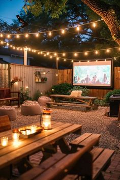 an outdoor movie is set up in the backyard with string lights strung across the fence