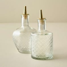 two clear glass bottles with gold caps