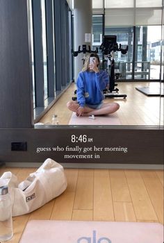 a woman sitting on top of a yoga mat in front of a mirror with a quote