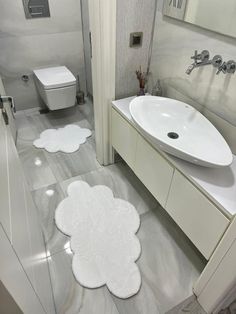 a bathroom with two white rugs on the floor next to a sink and toilet