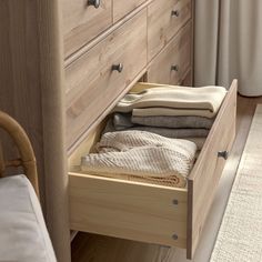 an open drawer in a wooden dresser next to a bed