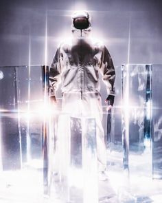 a man standing in front of mirrors wearing a white coverall and protective gear on his face