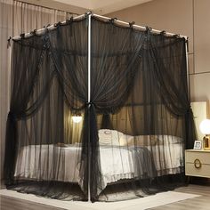 a bed with sheer curtains on the top and bottom, next to a night stand