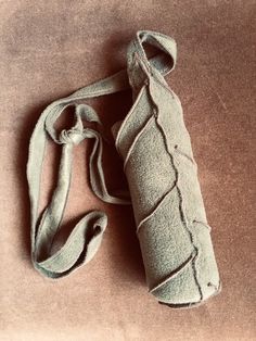 a roll of fabric sitting on top of a brown floor next to a bag with straps