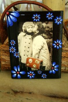 a photo frame with blue flowers on it and a red suitcase in the foreground