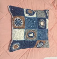 a crocheted blue and white pillow on a pink bed