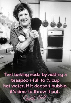 an older woman standing in a kitchen holding a frying pan and looking at the camera