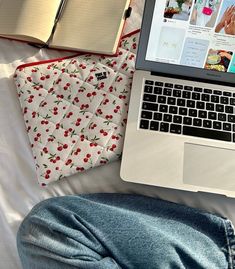 an open laptop computer sitting on top of a bed next to a book and notebook