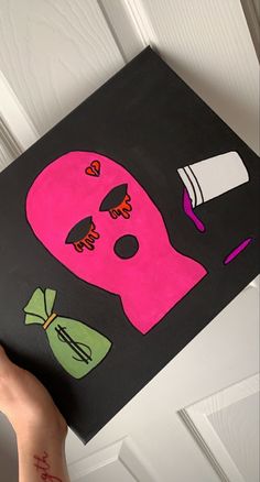 a person holding up a pink and black painting on a door frame that has been painted